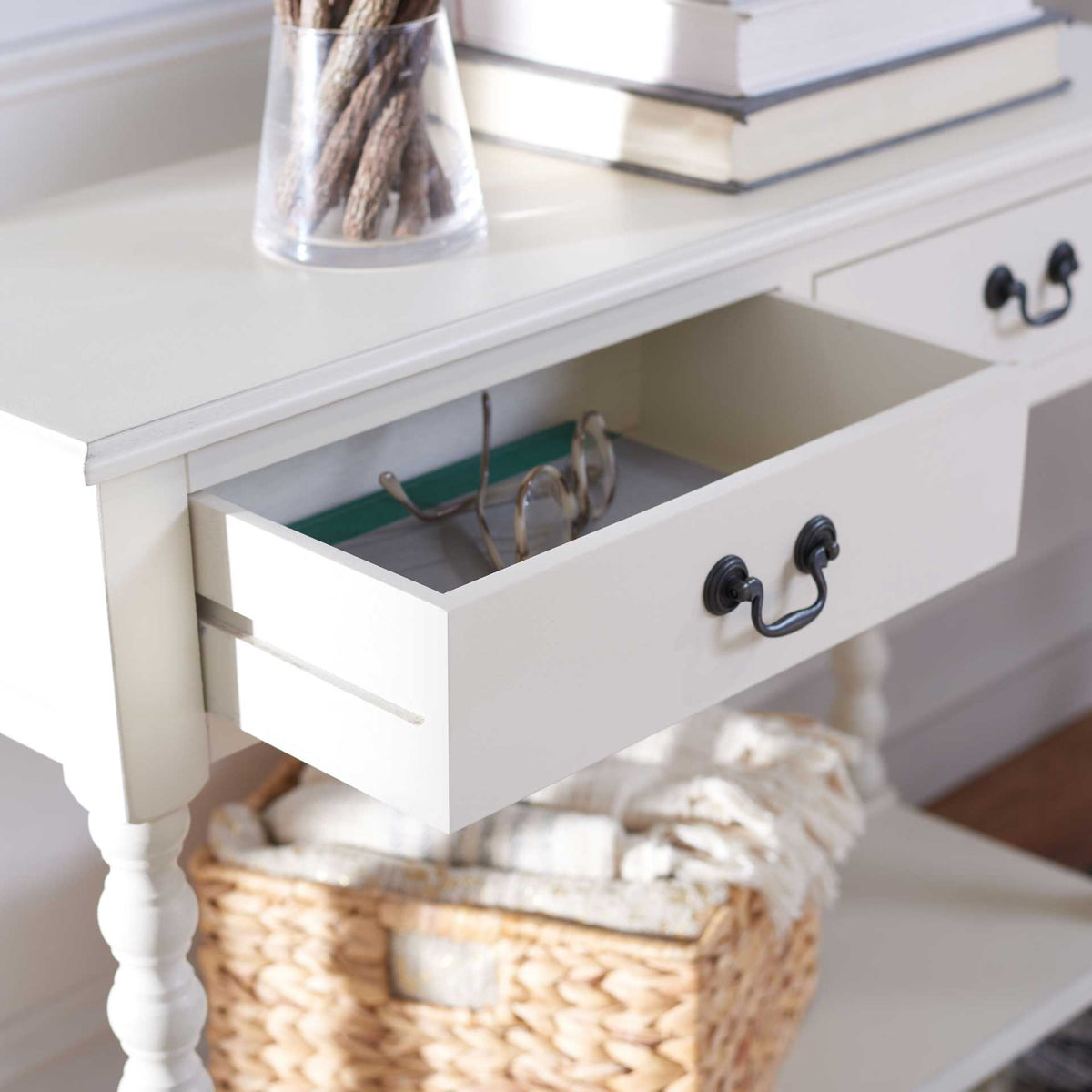 Open white drawer holds small essentials beneath a smooth tabletop with an antique black pull.