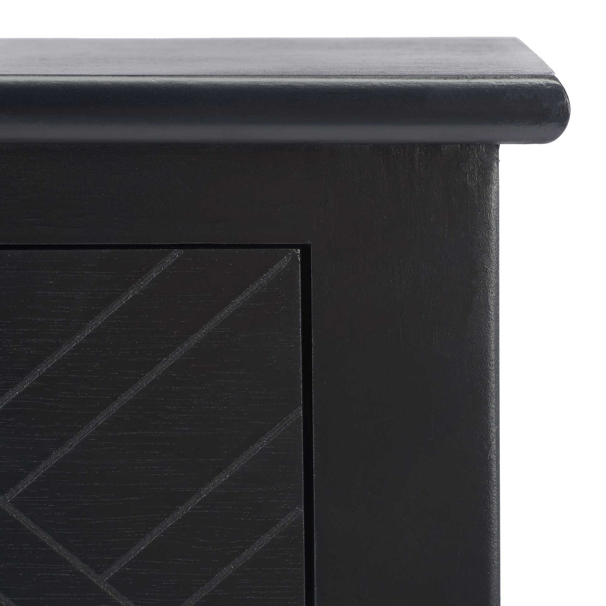 A softly rounded tabletop edge meets a smooth black frame and a grooved geometric drawer front
