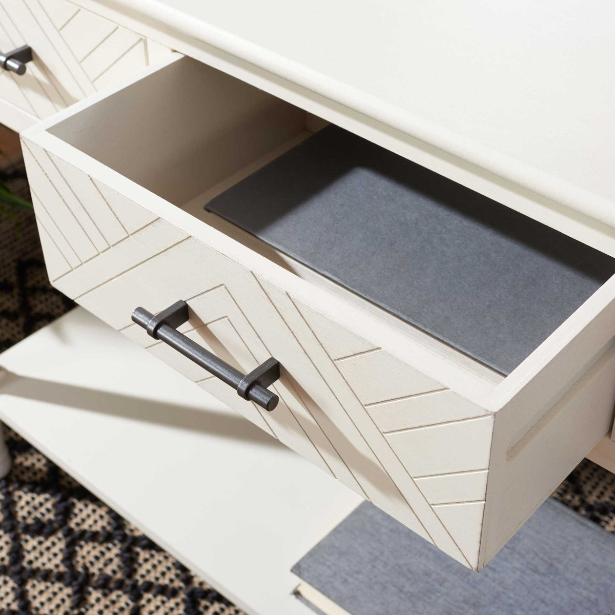 An open patterned drawer offers storage beneath the white wood top, accented by dark metal hardware