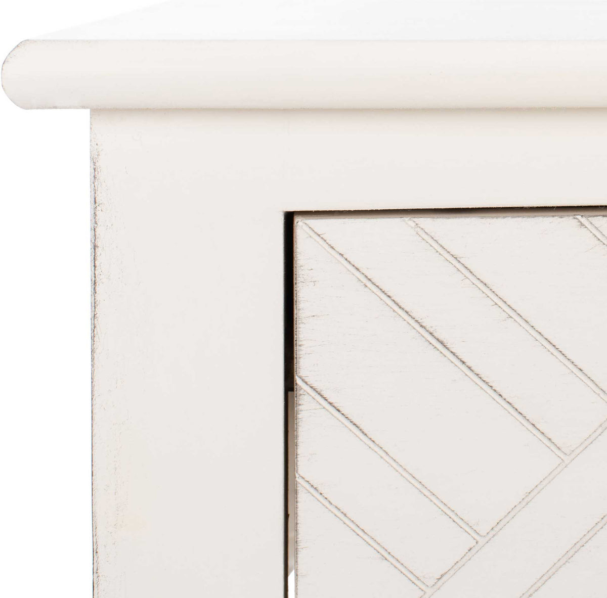 Softly distressed white paint traces the curved top edge and carved herringbone drawer grooves