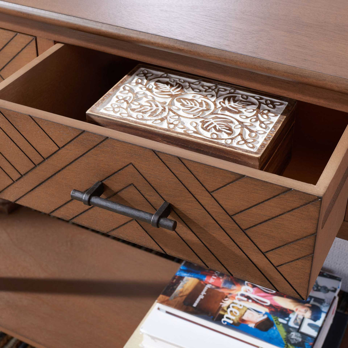 An open herringbone drawer holds a decorative box, pairing hidden storage with graphic wood detailing