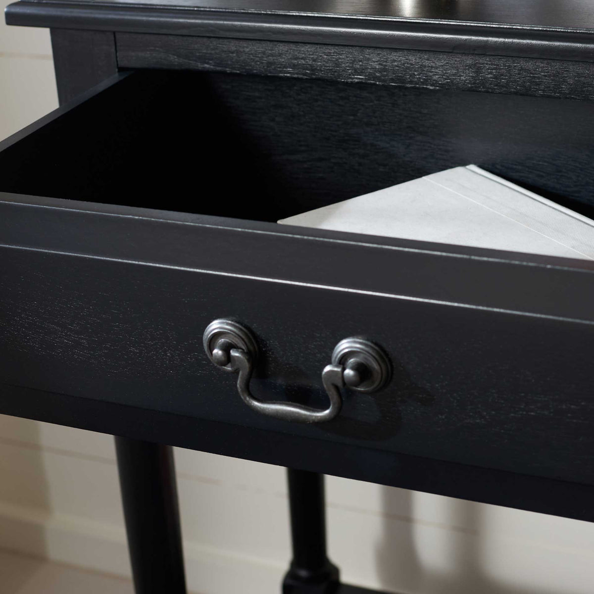 An open black drawer reveals a handy space for essentials beneath the console tabletop.