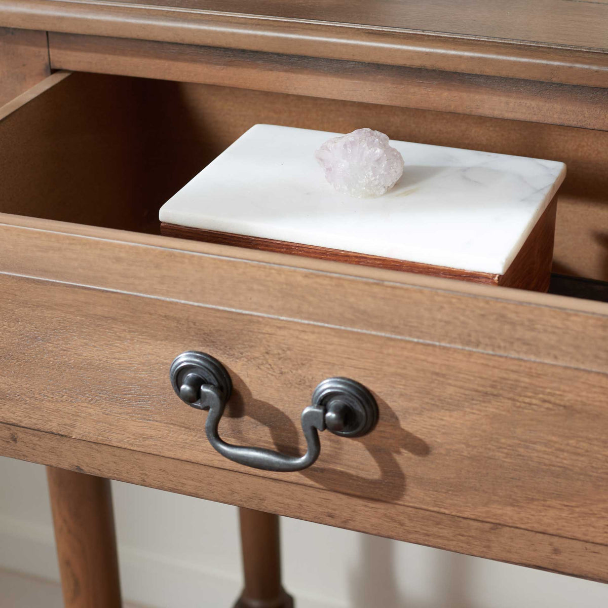 The open brown drawer holds small keepsakes behind a classic dark metal pull.