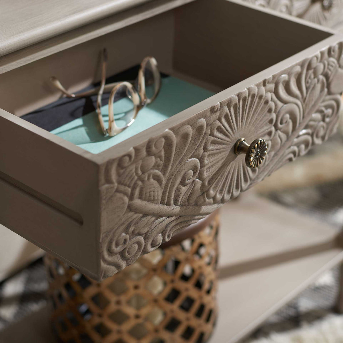 Intricate floral carving and a metal knob dress a roomy drawer for glasses and small essentials.