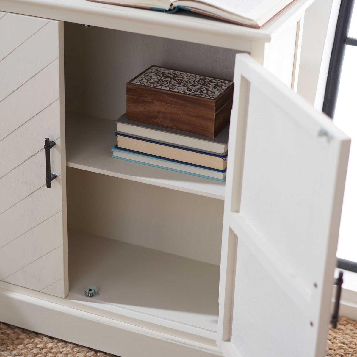 A fixed shelf divides the white cabinet's interior into spaces for books and treasured accents.