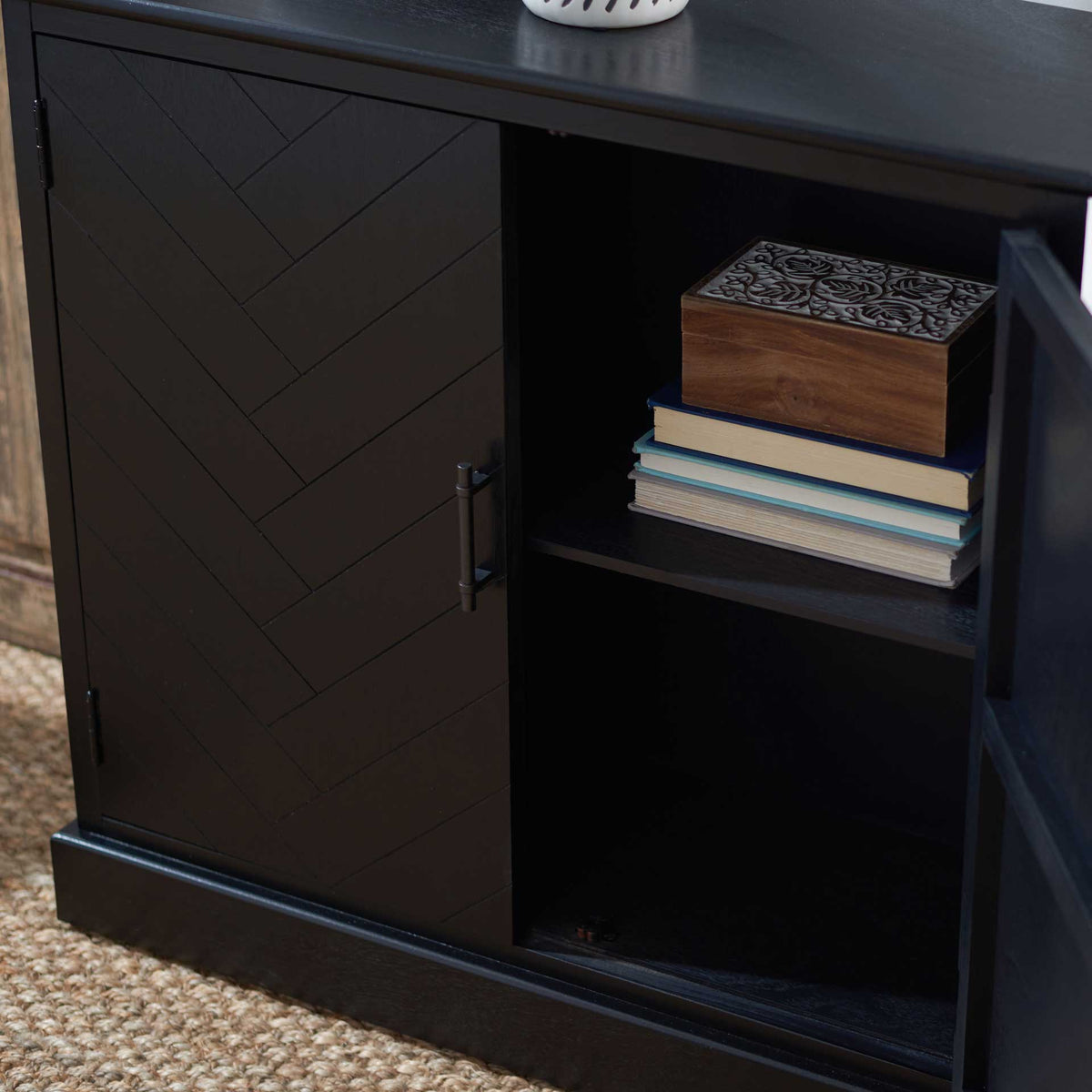 Books and a decorative box fit neatly on the fixed shelf inside this black sideboard.