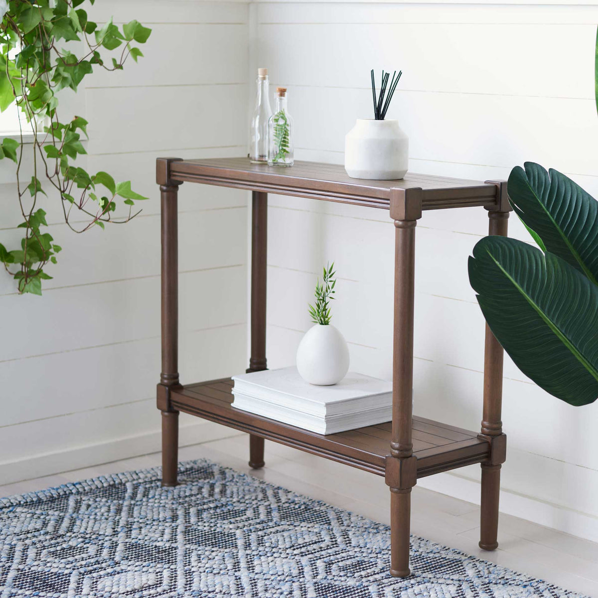 Books and small decorative accents rest on the brown console's top and lower shelf.