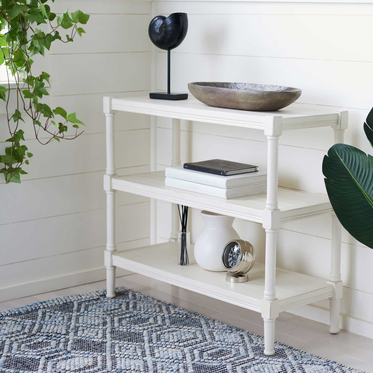 A white three-tier console offers airy display space for books and decorative pieces.