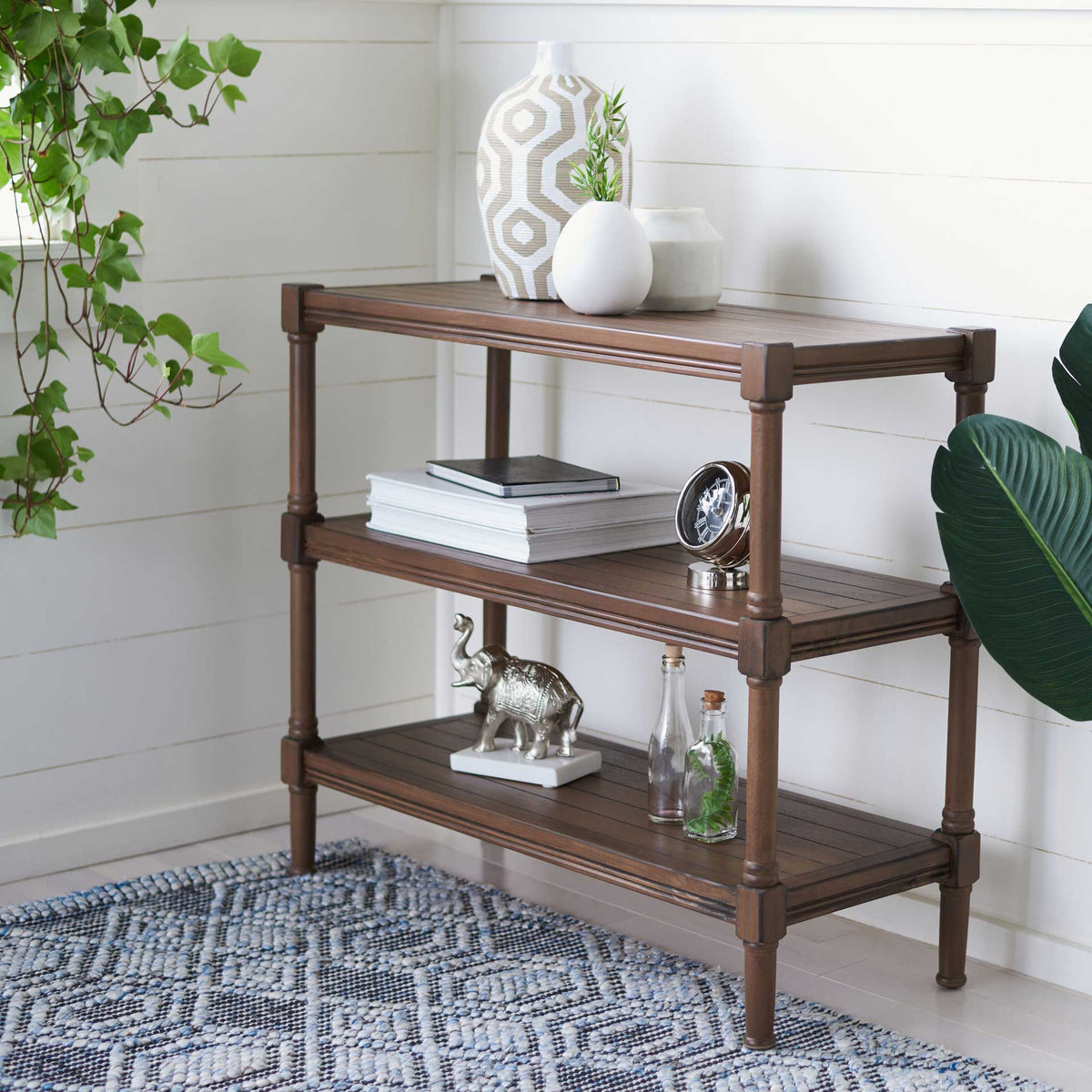 Warm brown shelves hold books, vases, and accents beside white paneled walls.