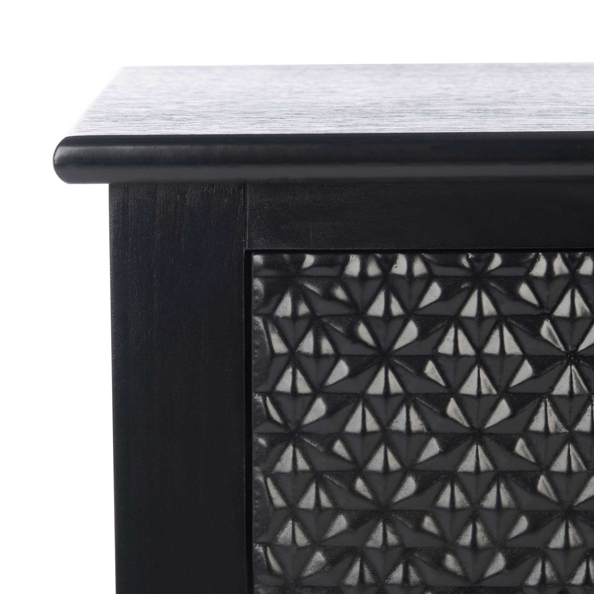 A softly rounded black tabletop frames the dimensional geometric pattern on the drawer front.
