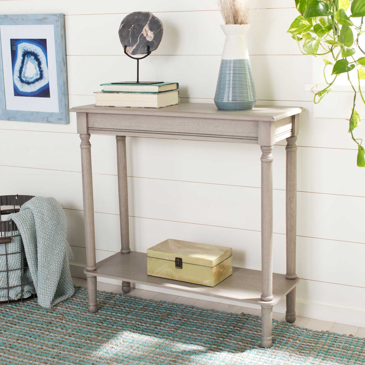 The pale greige console holds books and decor above a practical lower display shelf.