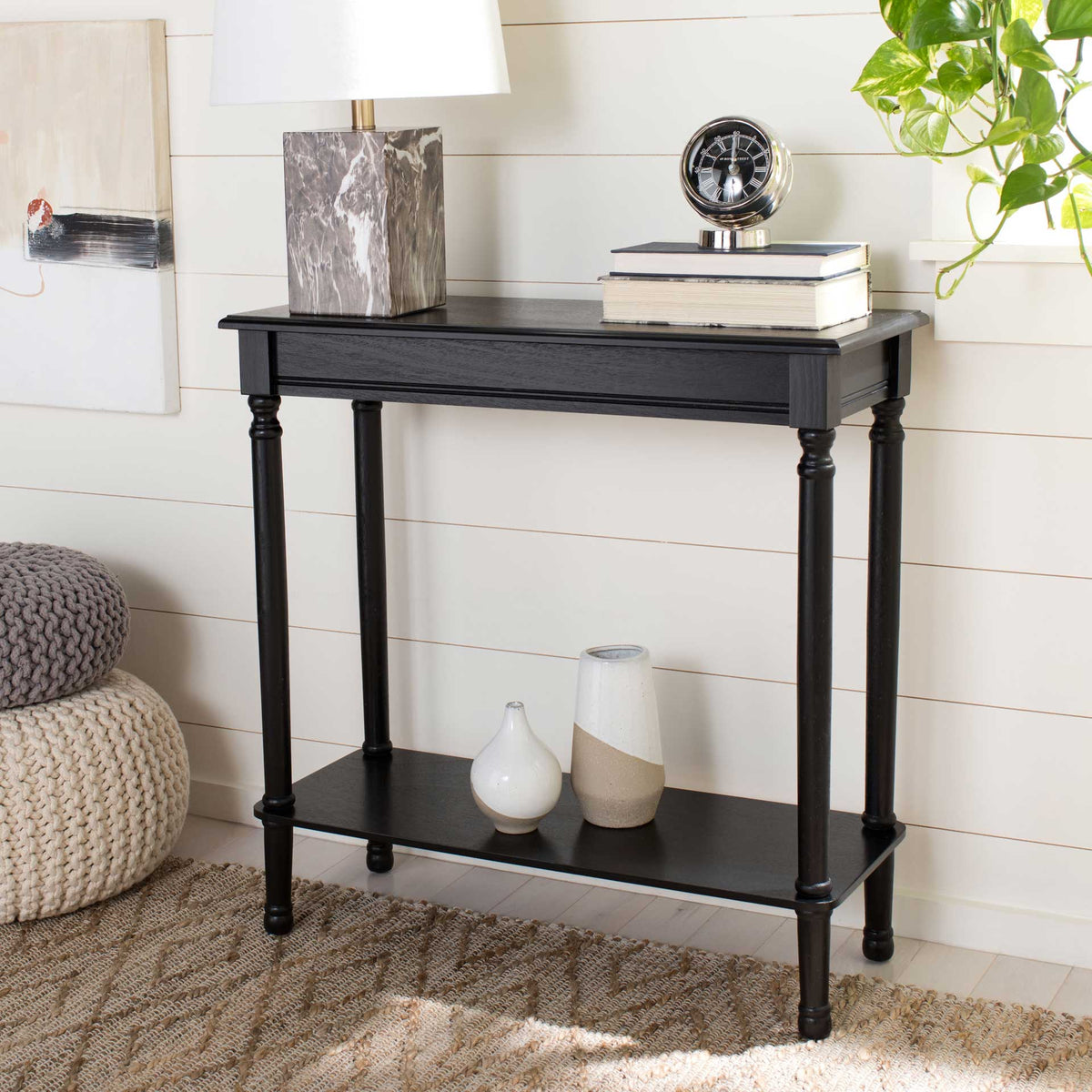 The black console offers space for a lamp and books, with a lower shelf for extra decor.