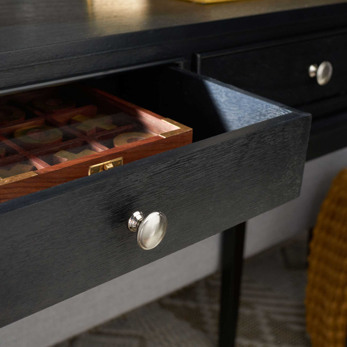 An open black drawer holds a wooden organizer beneath the console's dark tabletop