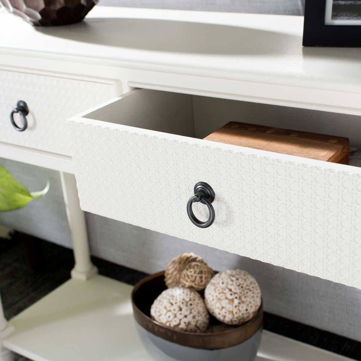An open white drawer reveals storage behind its textured front and dark ring pull