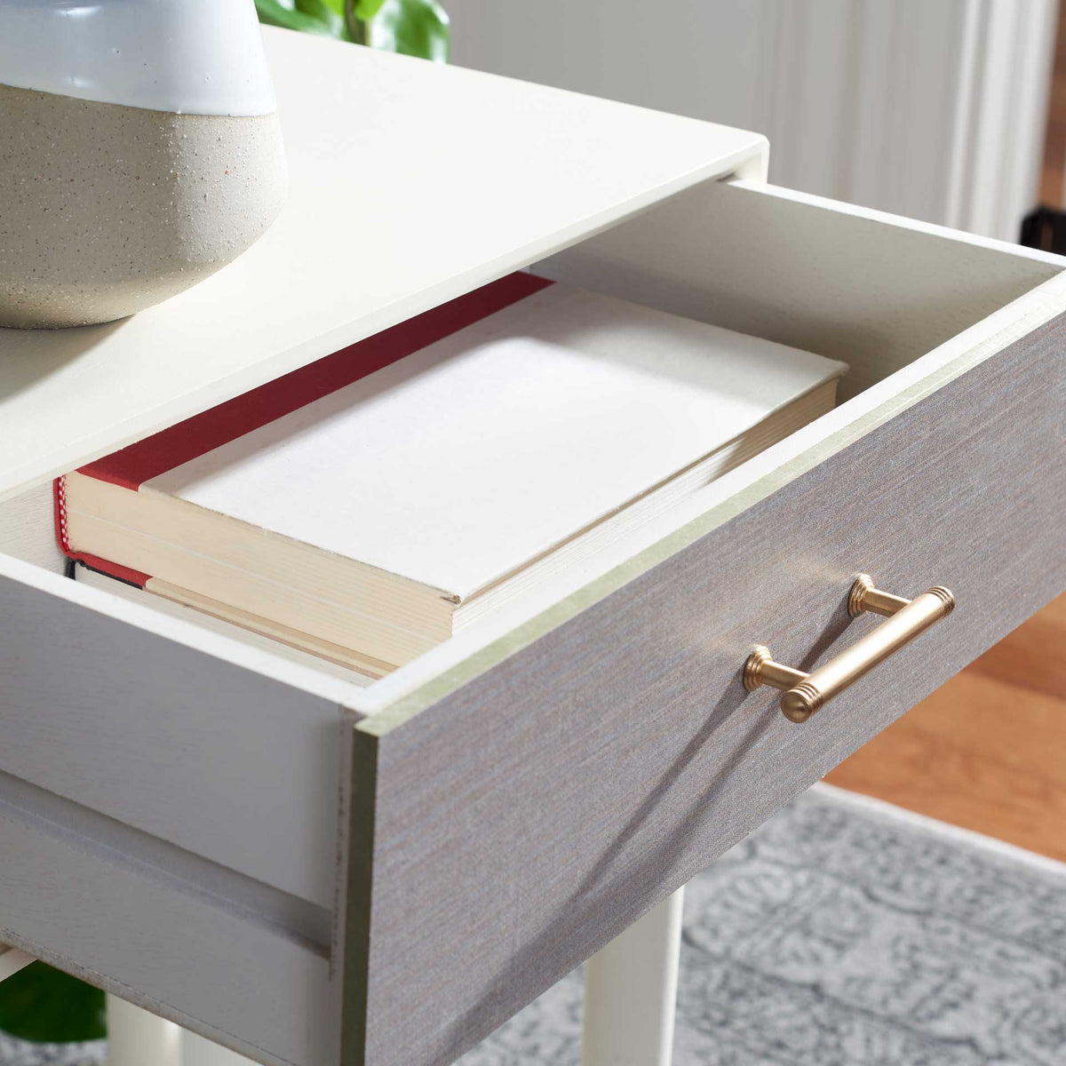 A roomy white drawer stores a book within easy reach beneath the pale tabletop