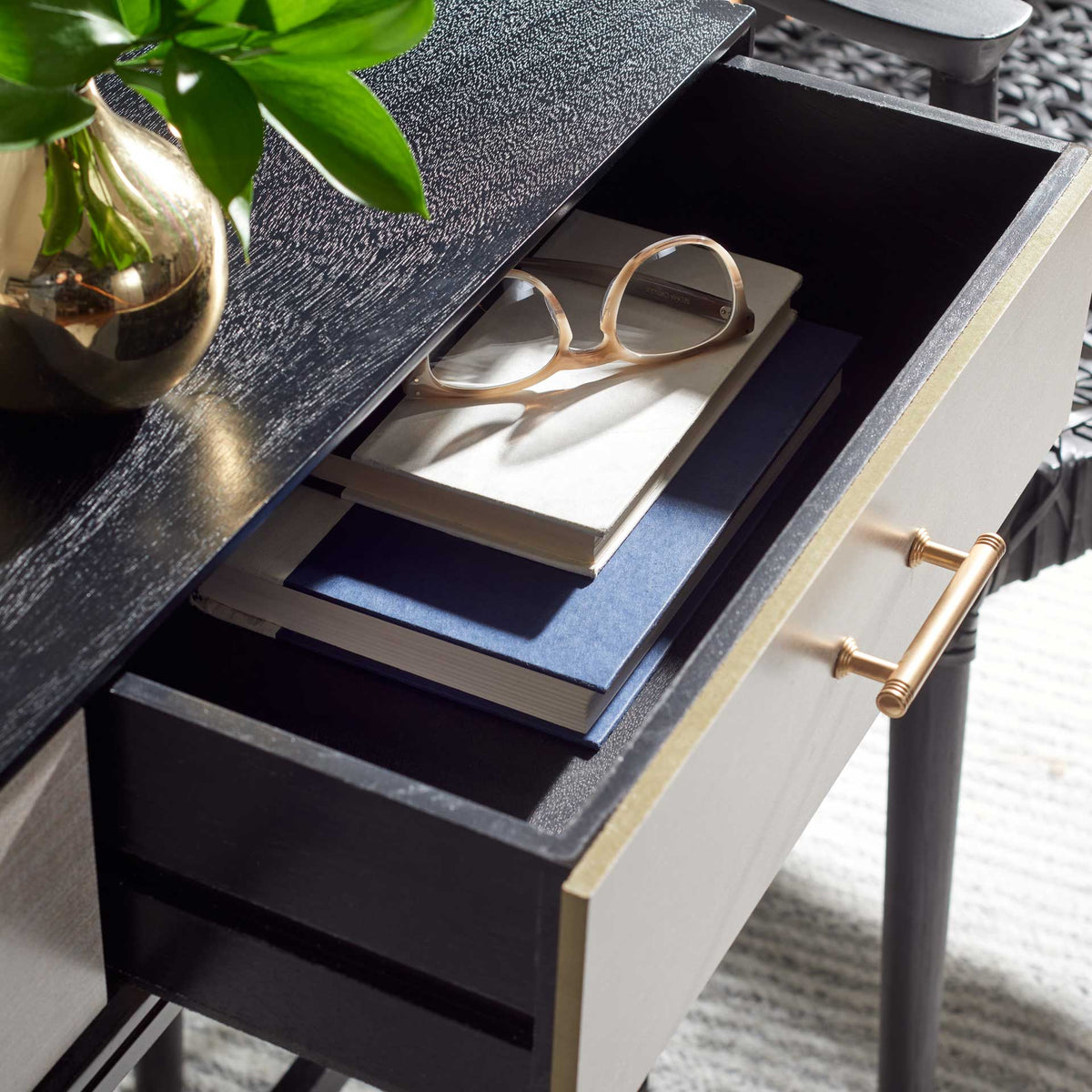 A deep drawer keeps books and eyeglasses handy beneath the sleek black top