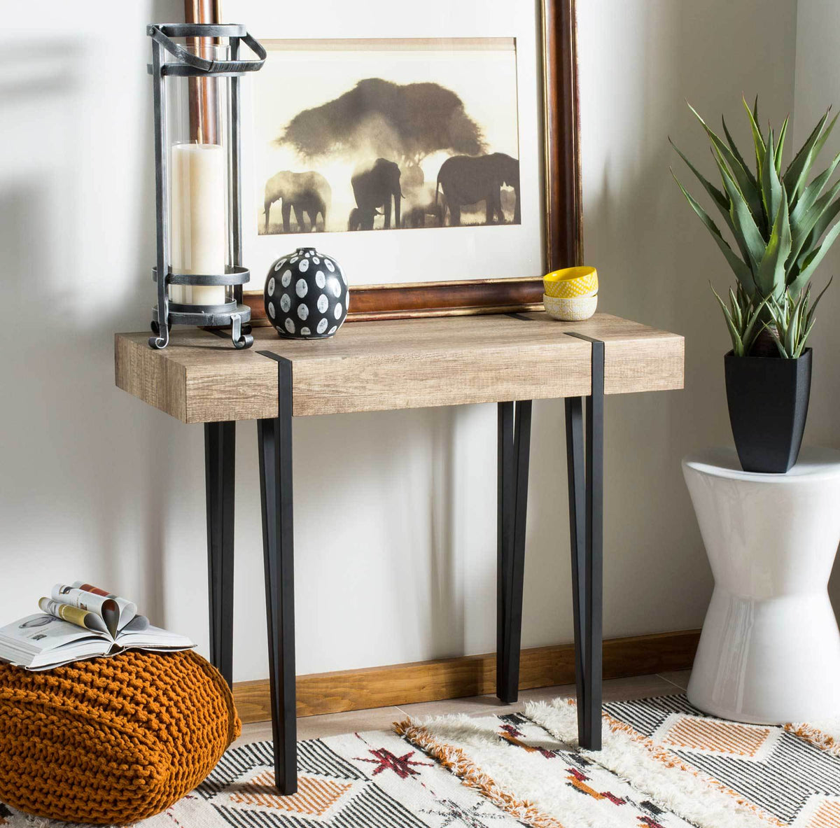 A weathered brown console table offers display space above tall black legs and a slim, airy base.