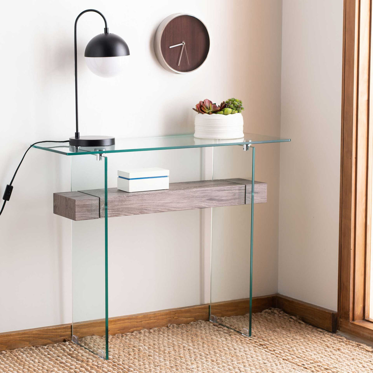 An airy glass console with a gray wood-look shelf brings gentle texture to a bright room.