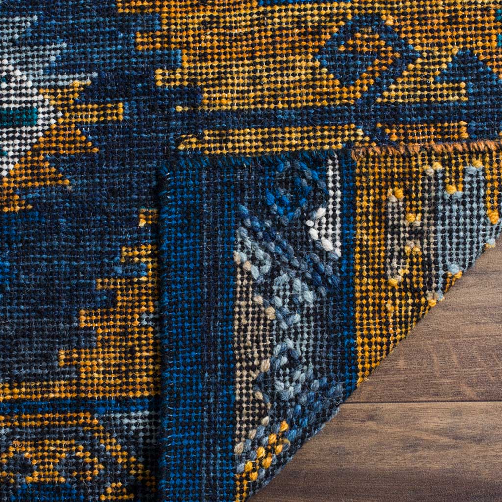 A turned-back corner reveals the rug's woven underside beneath its blue and gold geometric design.