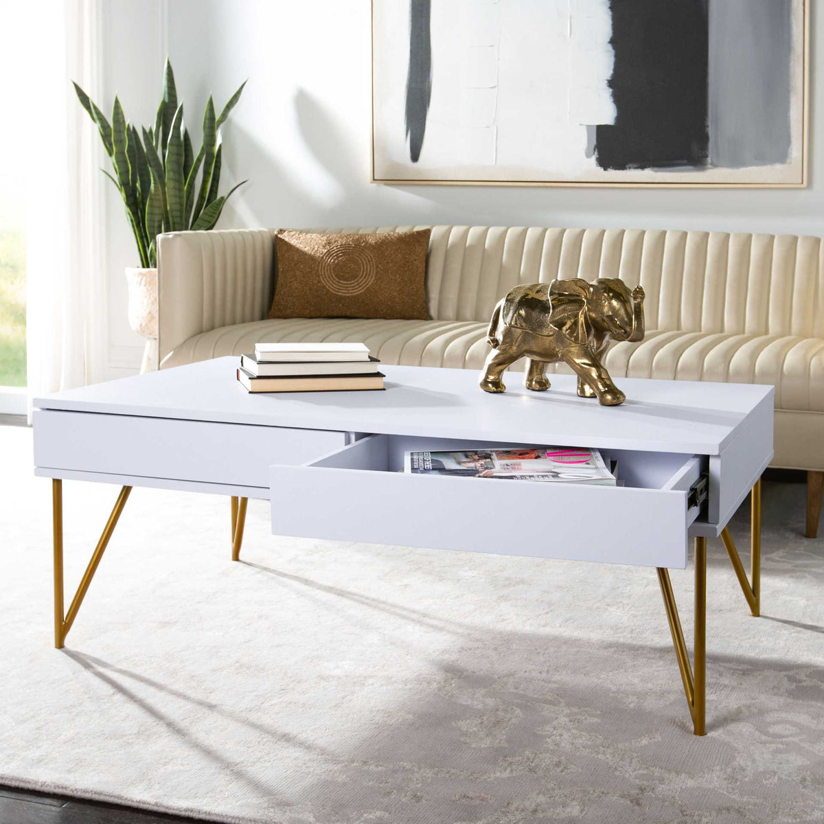 A spacious drawer stores magazines beneath the white tabletop, framed by slim gold legs.