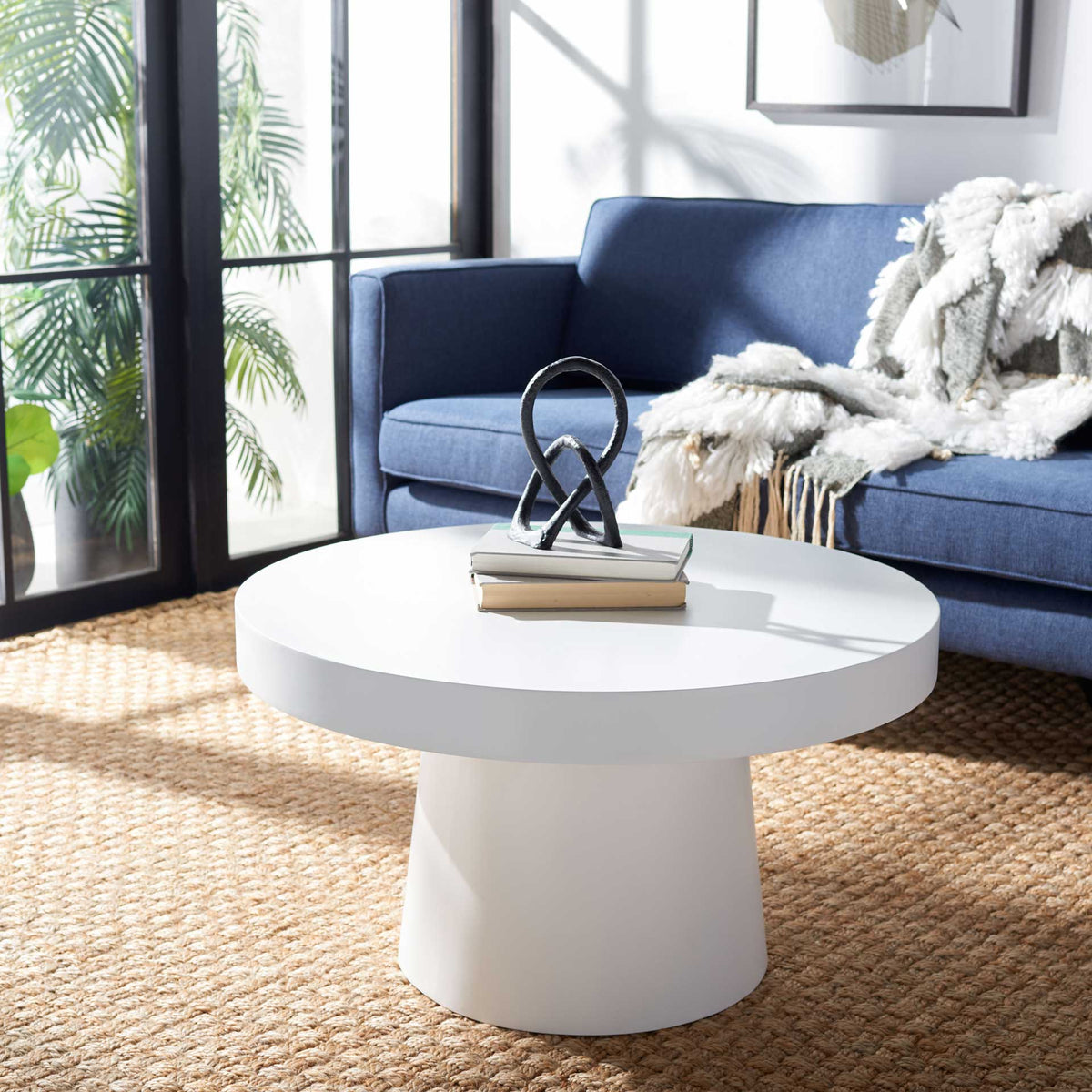 A white pedestal coffee table brings soft, sculptural curves to a modern living room.