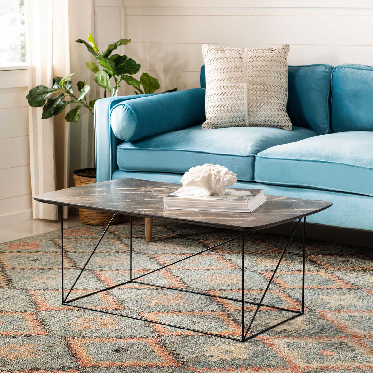 Dark veined tabletop and airy black iron base bring modern contrast to the living room.