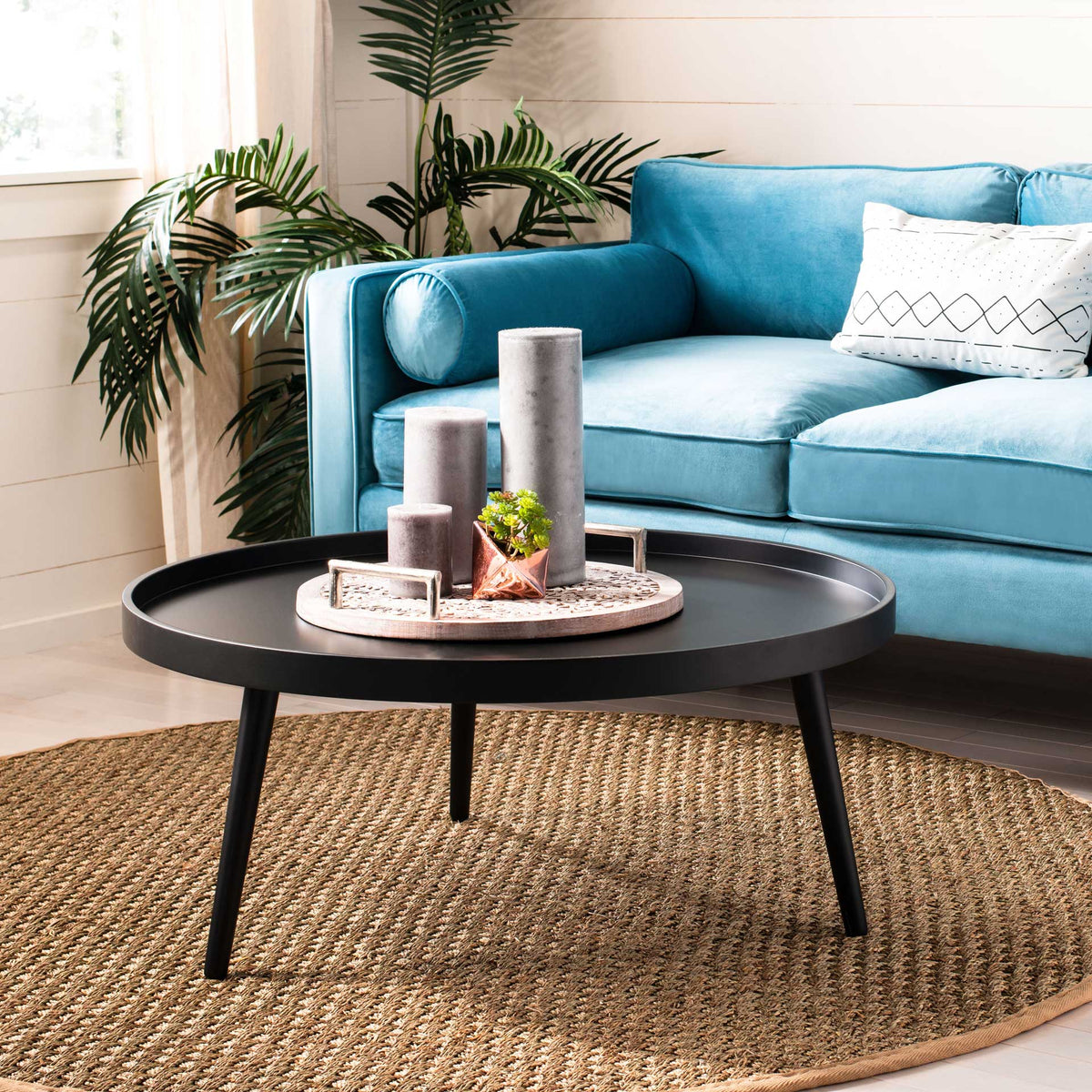 A low black coffee table with a raised tray edge anchors a bright living space