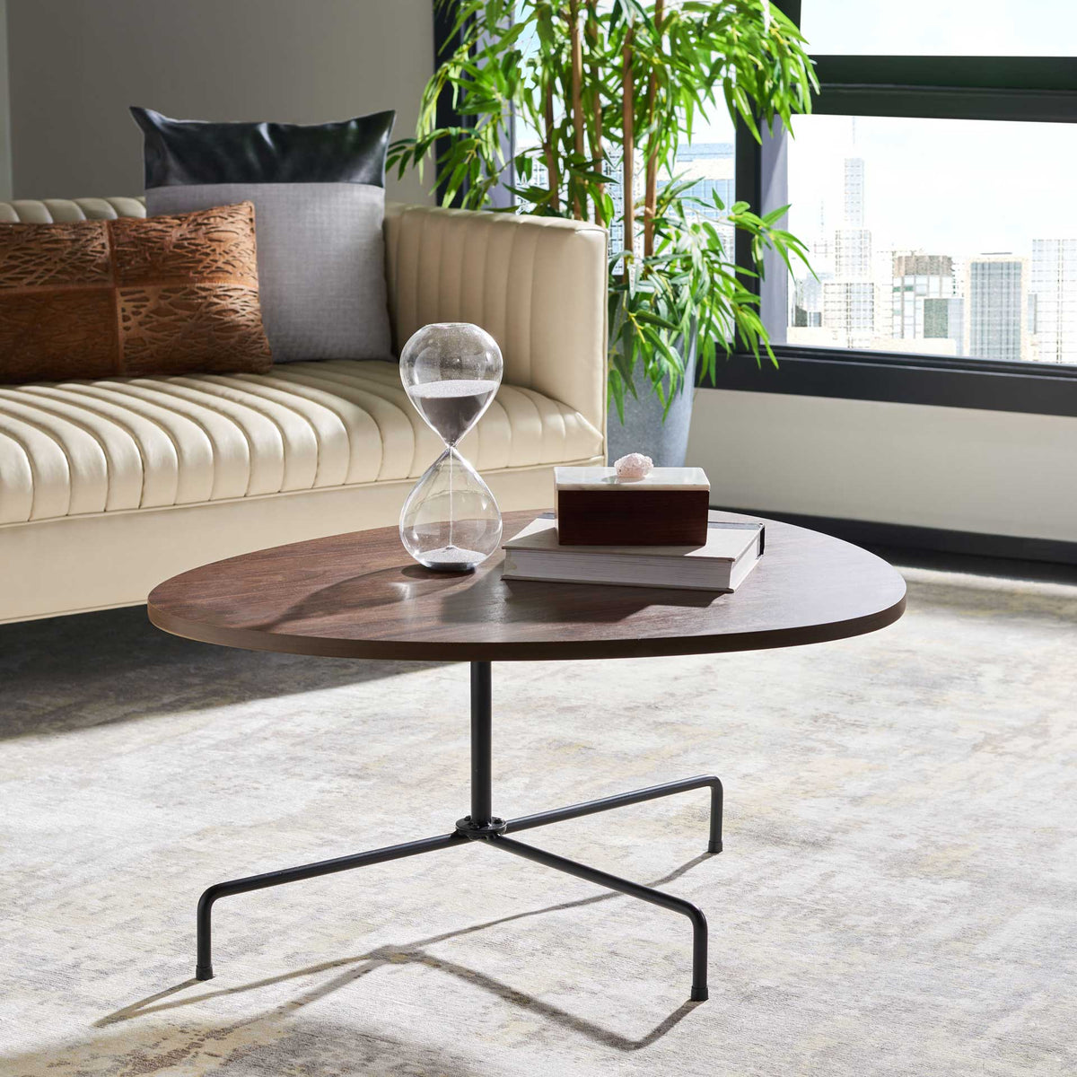 A walnut veneer tabletop and slender black tripod base add warmth and airy style to a living room.