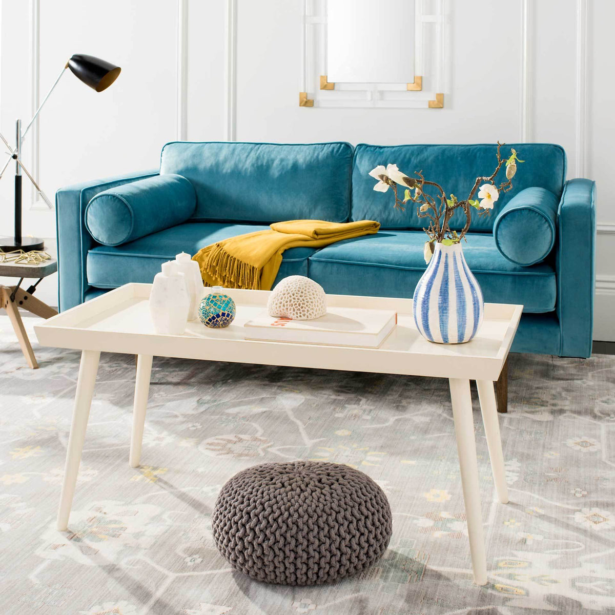 A bright white tray-top coffee table offers room for books, flowers and decor