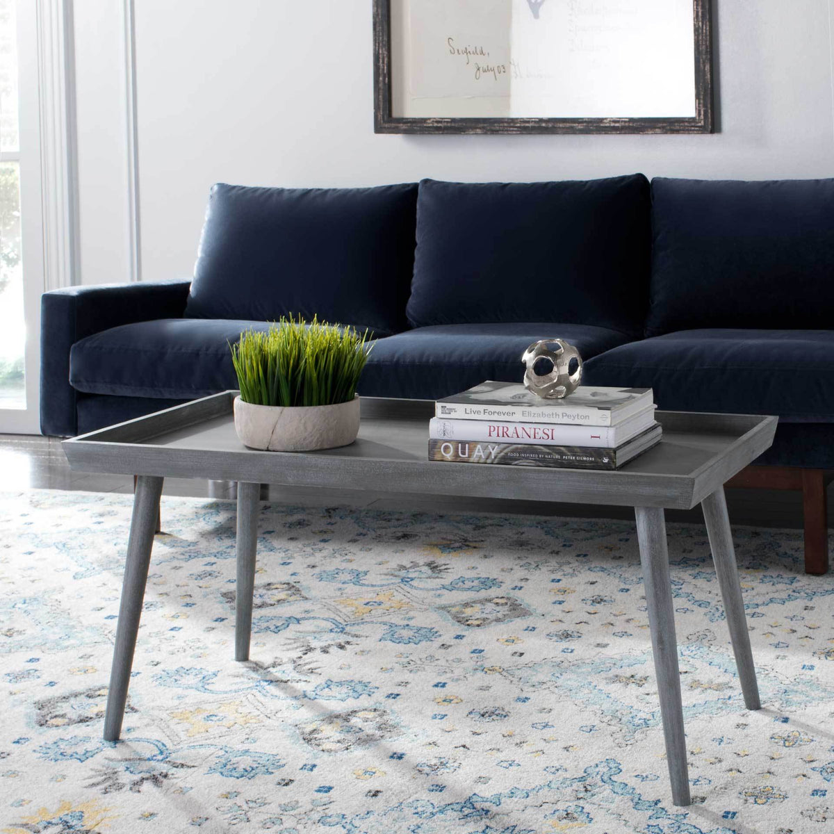 A slate gray tray-top coffee table anchors a living room with a wide display surface