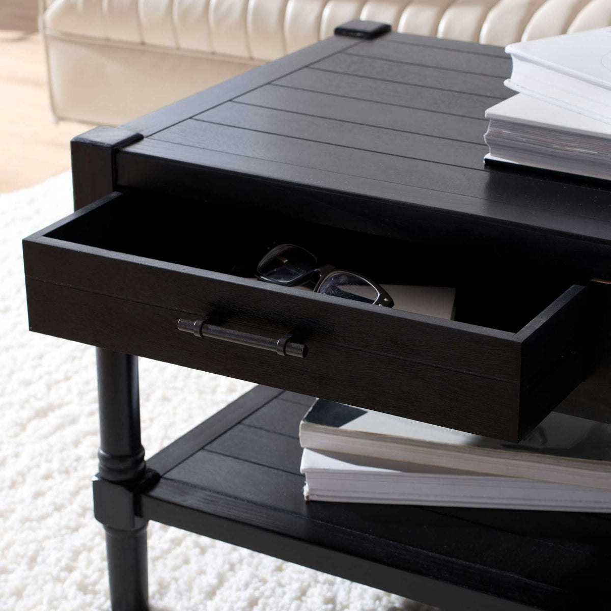 An open black drawer keeps eyeglasses and small essentials within reach above the lower shelf.