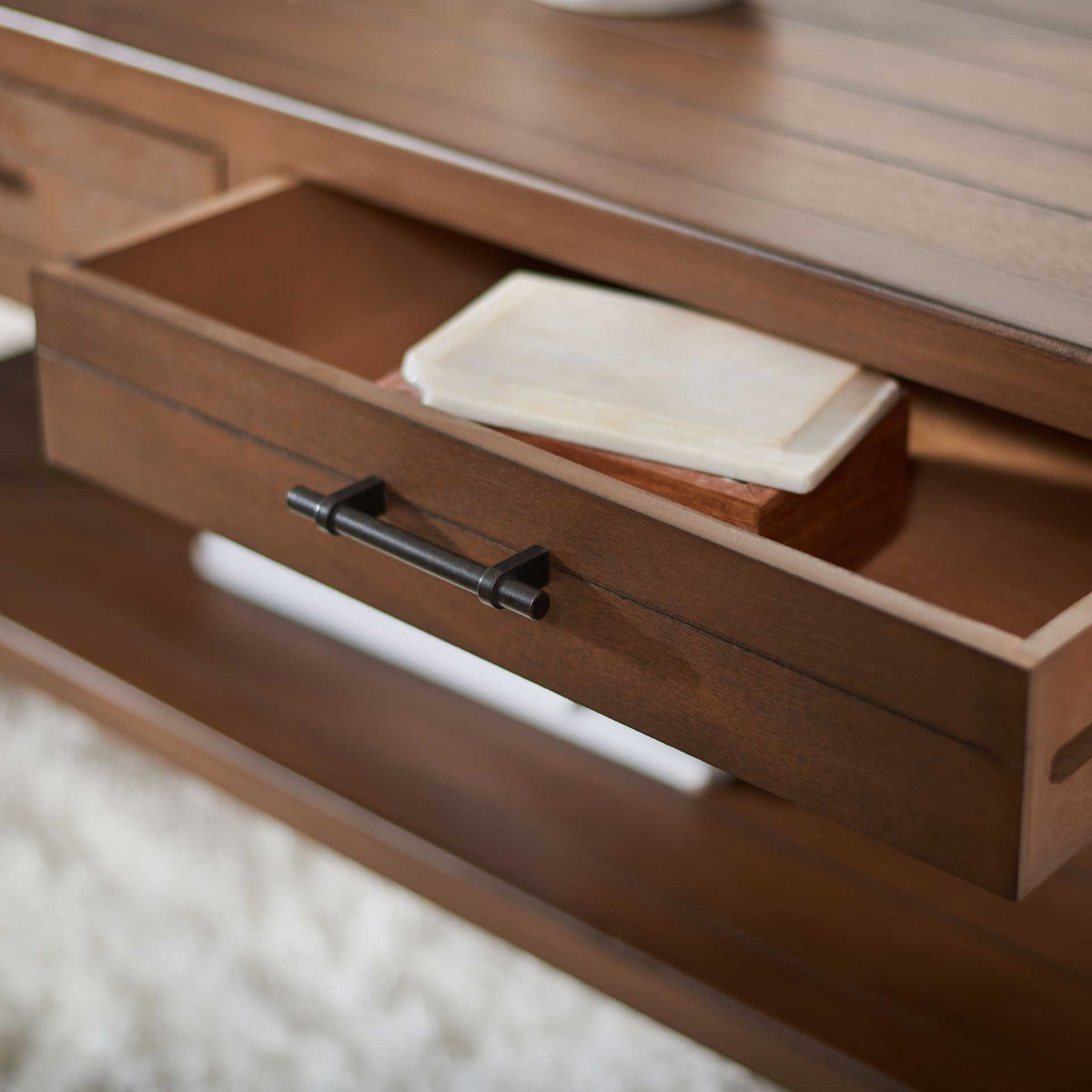 An open brown drawer offers discreet space for small essentials beneath the plank-style tabletop.