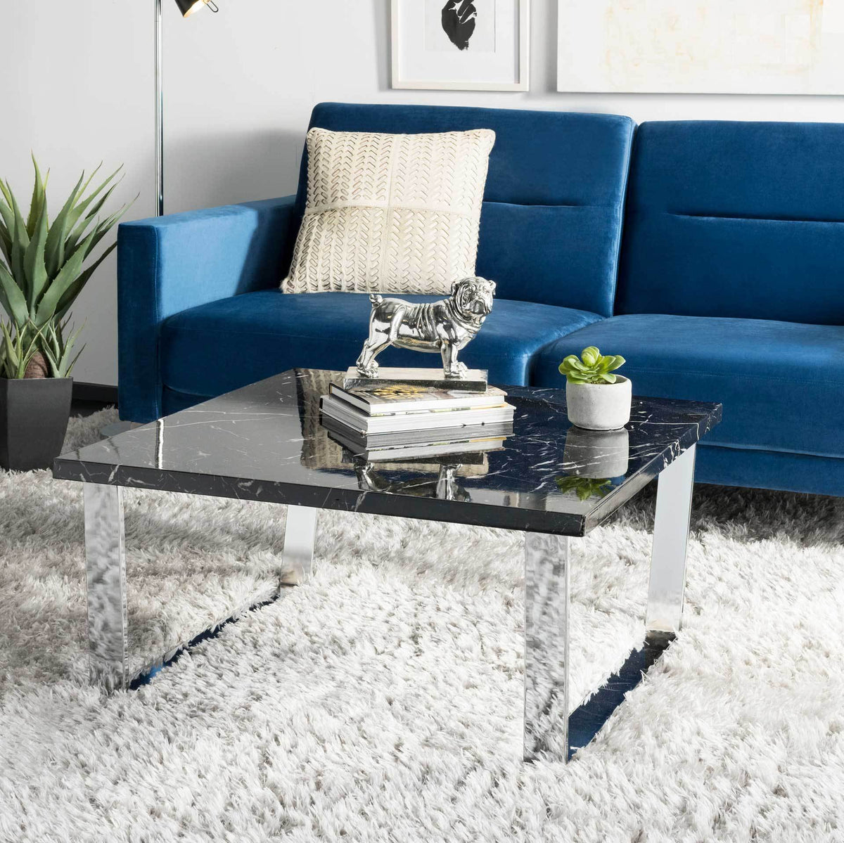 A glossy black marble-look top and gleaming chrome legs add sleek style beside a blue sofa.