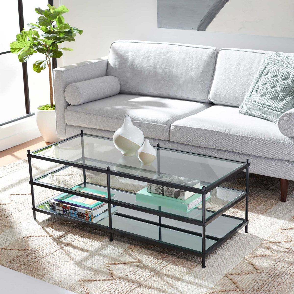A clear glass top displays decor while mirrored lower shelves hold books and add a bright, layered look