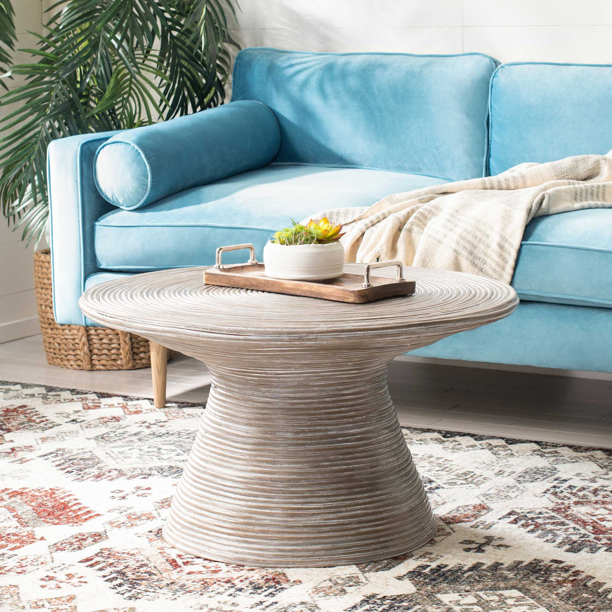 A grooved round top and curving pedestal bring organic texture to a living room.