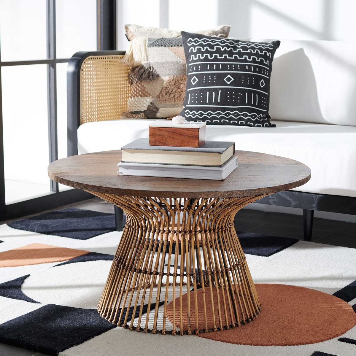 A woven rattan base brings warmth to the rustic round wood table in a relaxed living space.