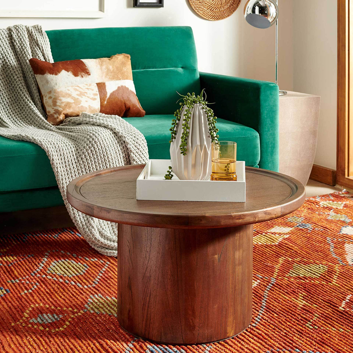A raised-rim tabletop and dark wood finish bring warmth to this low pedestal coffee table.