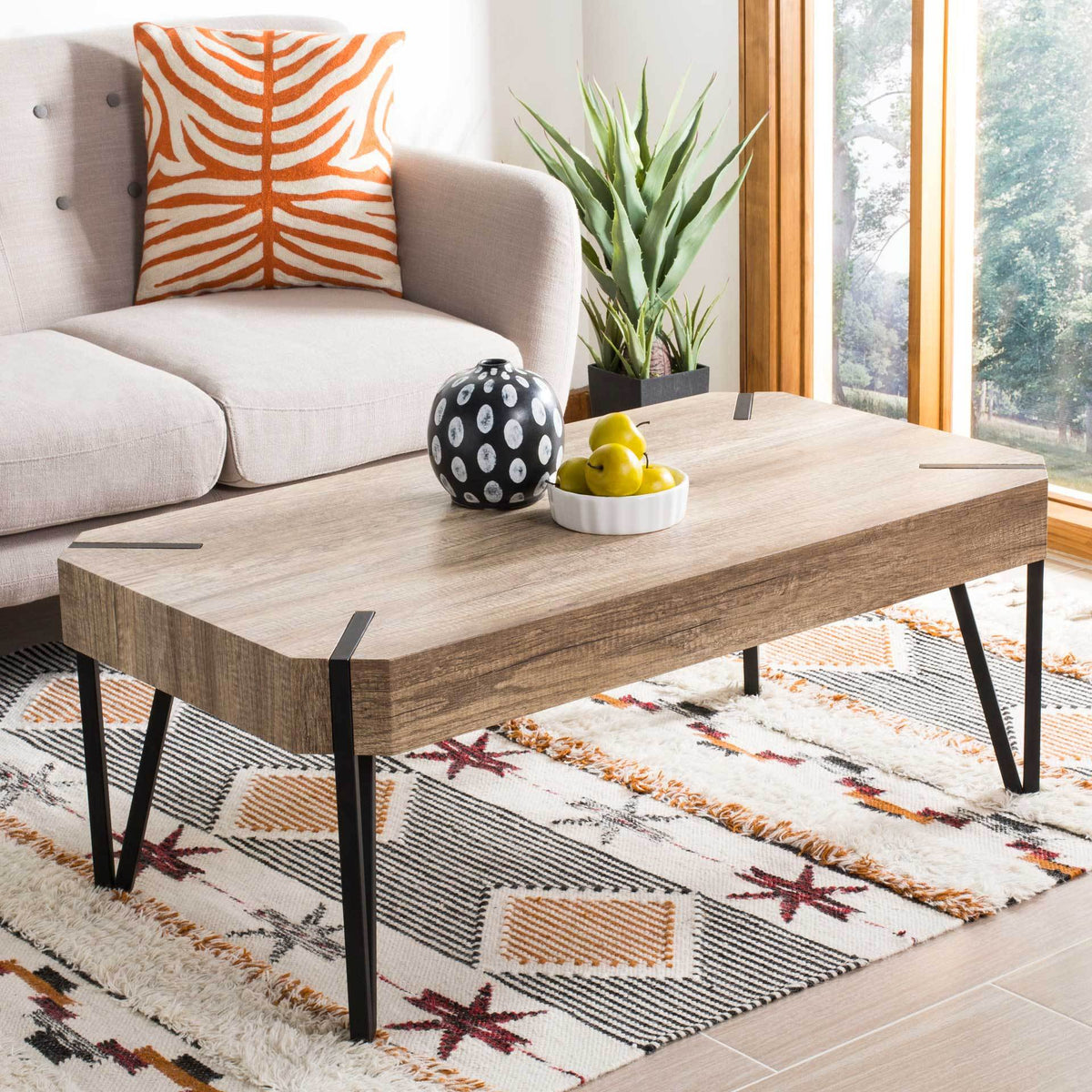 A low-profile coffee table brings warm wood-grain texture and bold black metal accents to a living space.