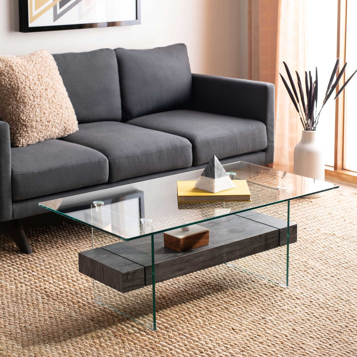 A smoky charcoal shelf anchors the transparent glass coffee table with modern contrast