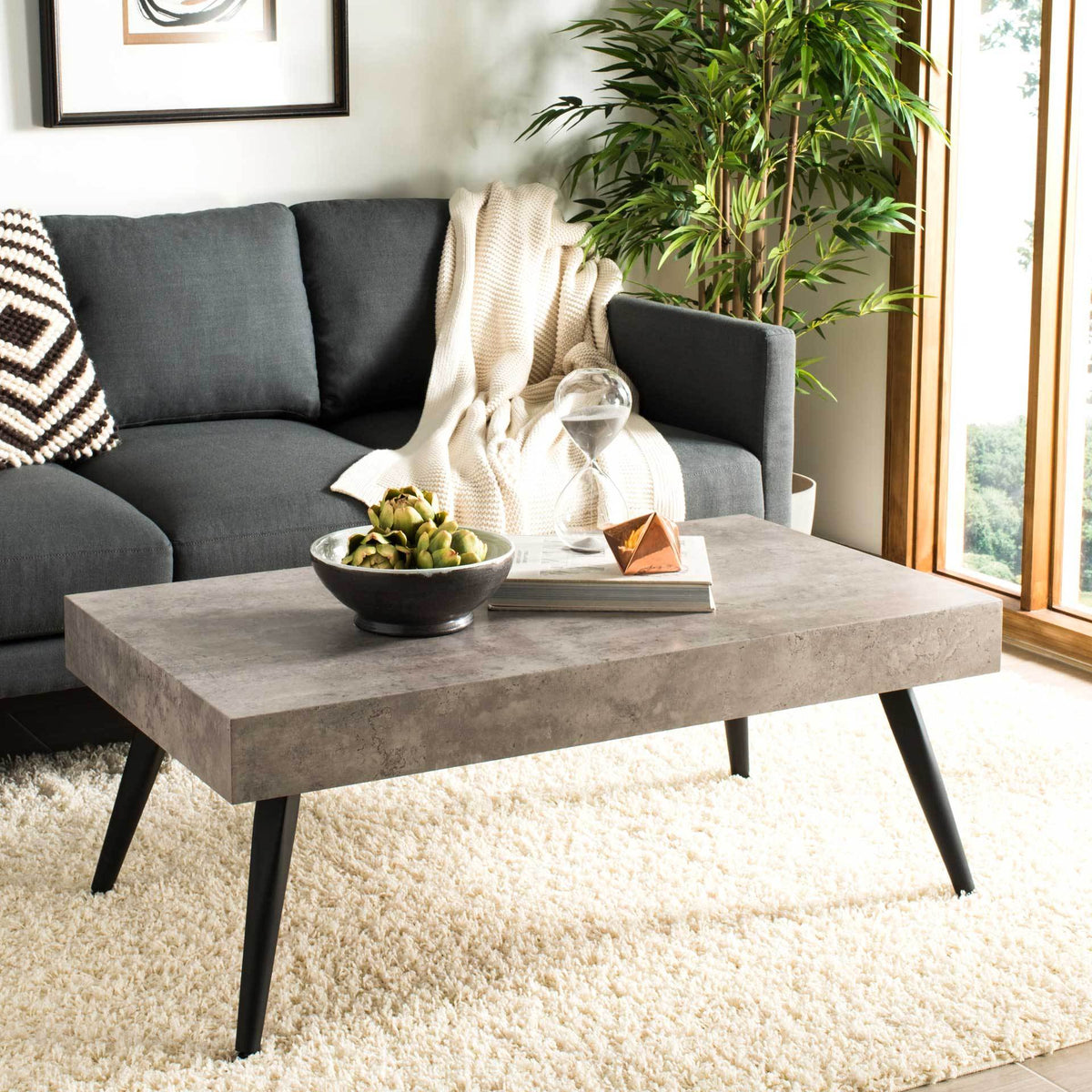 A broad concrete-look surface offers room for decor, while splayed black legs lend airy appeal.