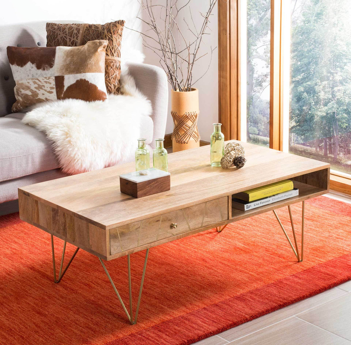 A smooth natural wood top and patterned drawer bring warmth to the airy brass-legged coffee table