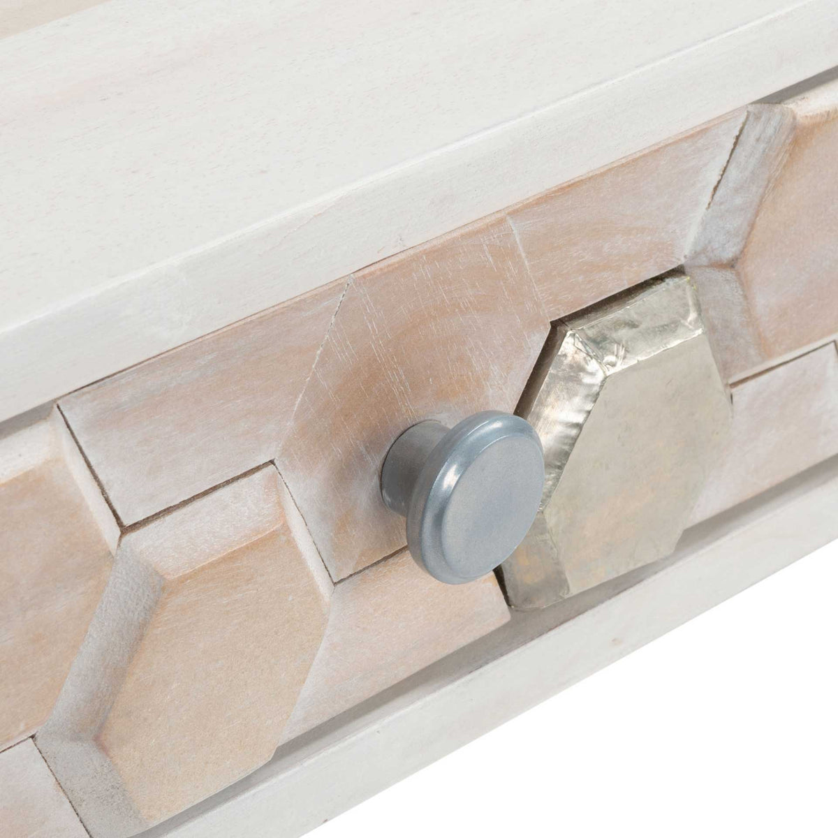 A round silver-tone pull stands out against pale carved hexagons and reflective metal inlays.