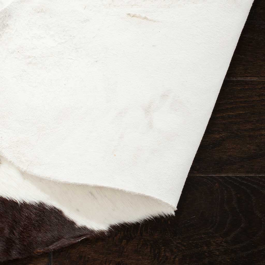 A cream hide underside meets dark fur at the edge of this black and white cowhide rug.