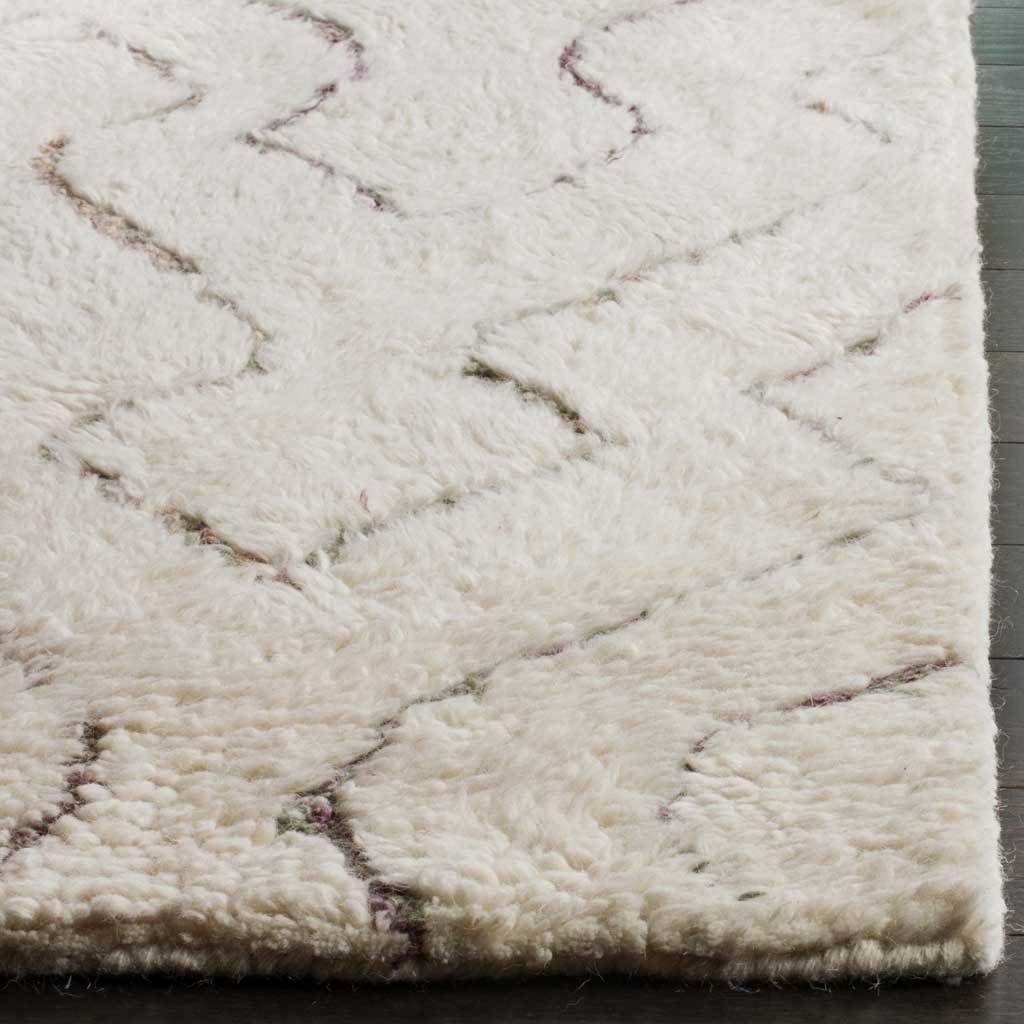 Thick, fluffy ivory fibers surround muted geometric lines and a neatly finished edge.
