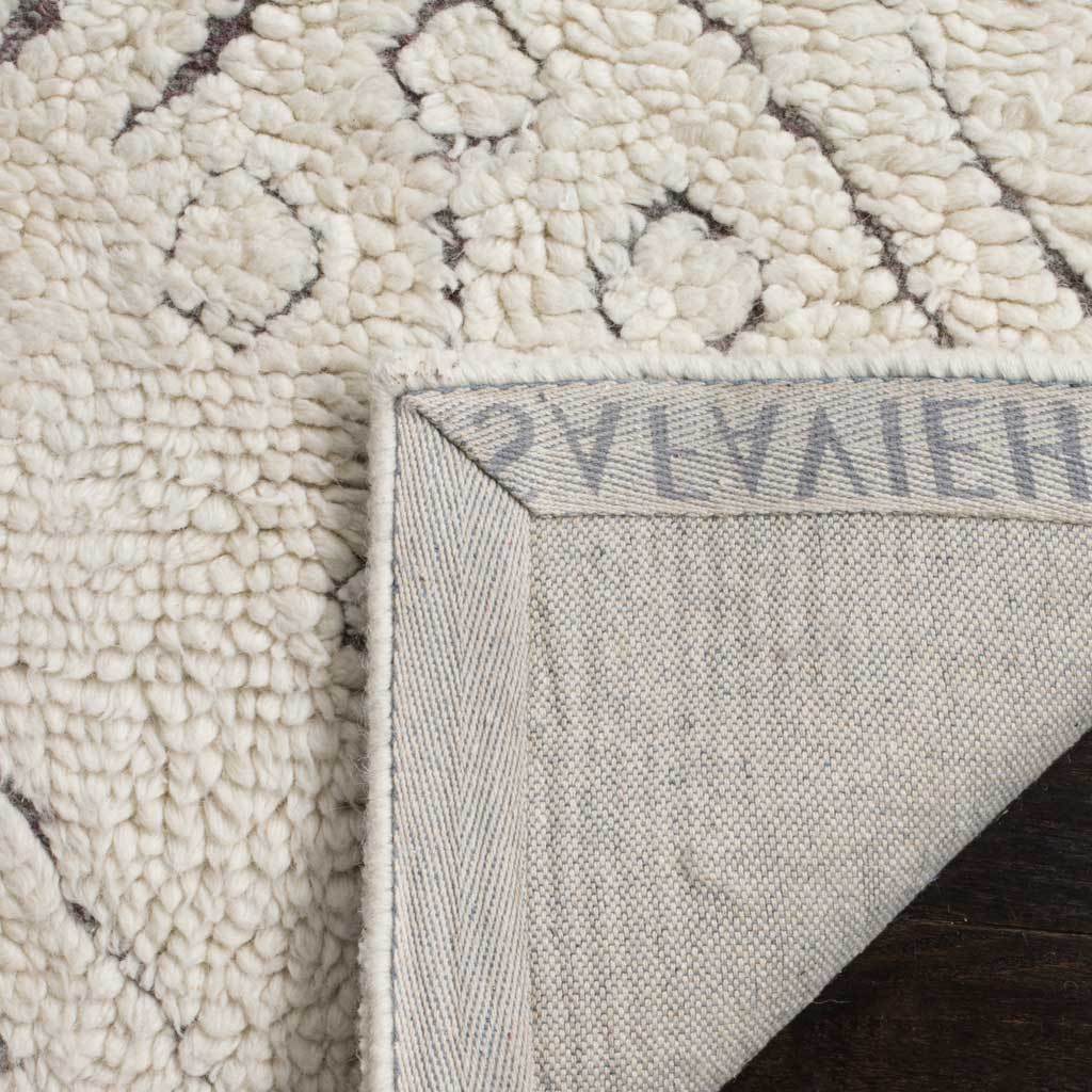 Folded rug corner reveals woven fabric backing beneath thick ivory pile and charcoal patterning