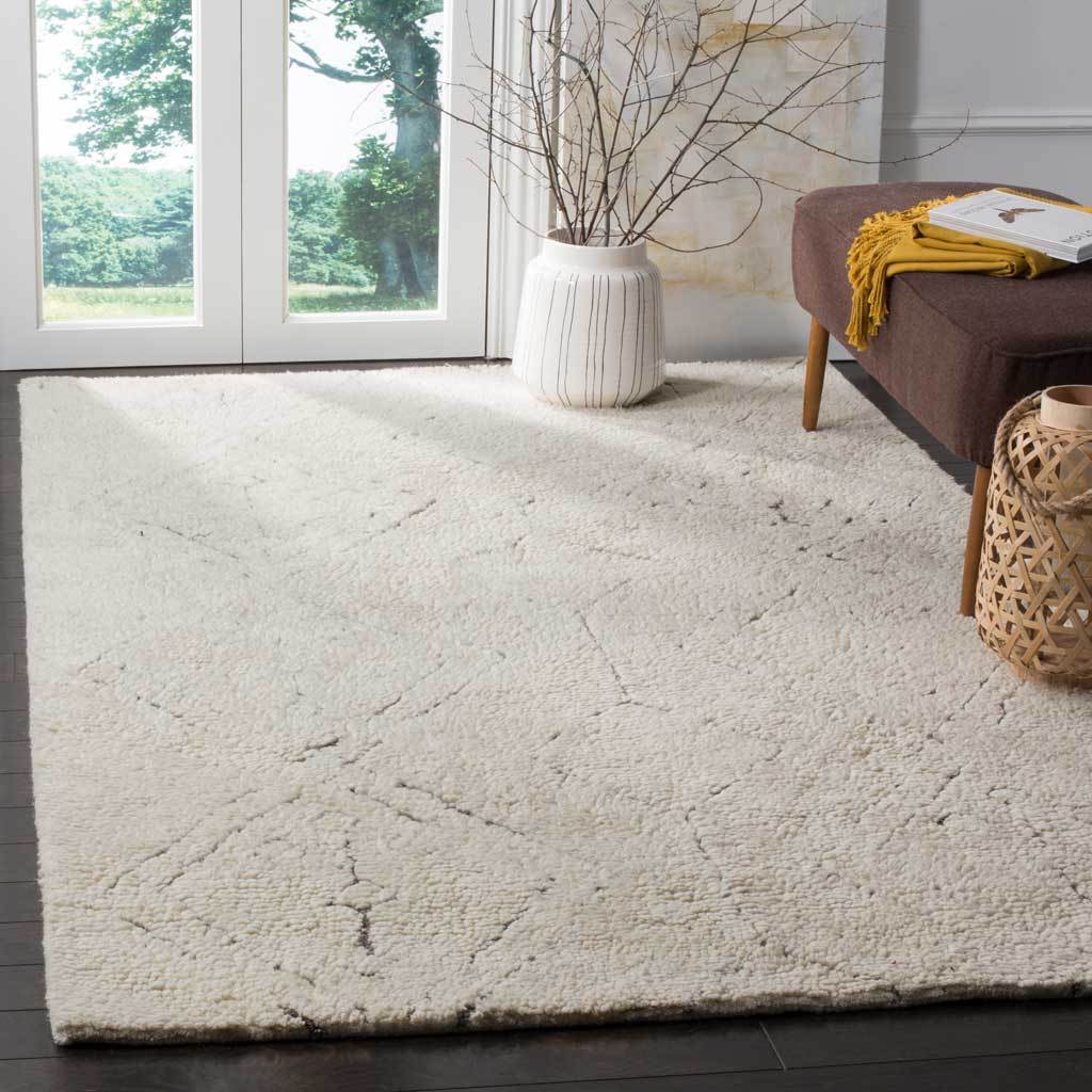 Plush ivory rug with subtle diamond linework adds warmth and texture beside a living room chair