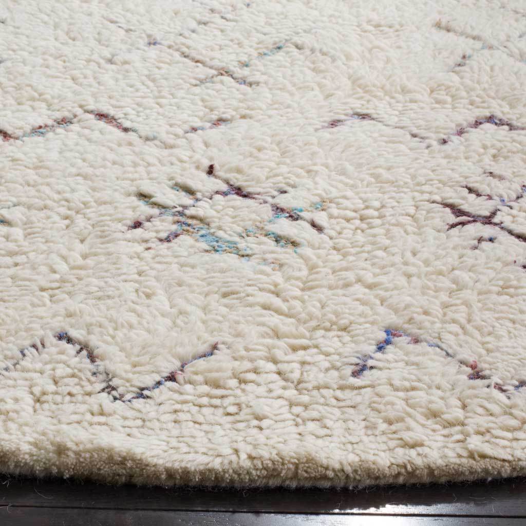 Dense ivory pile with delicate blue, purple, and teal motifs and a softly finished edge