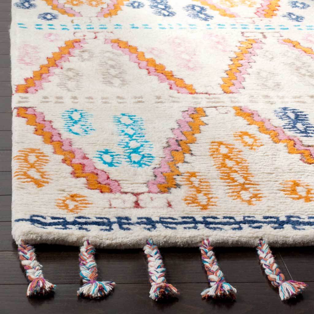 Braided multicolor tassels accent plush ivory pile, bold geometric lines, and a navy patterned border.