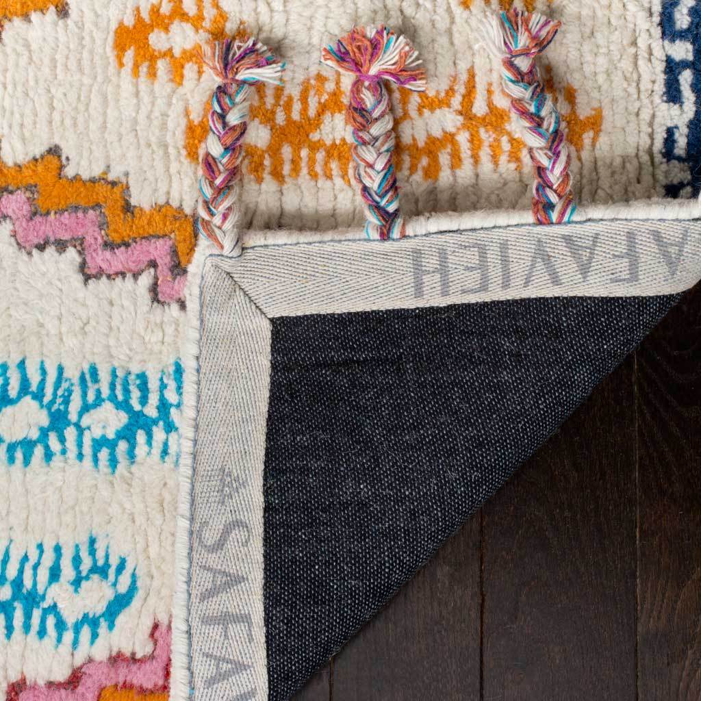 Dark woven backing and bound edges complement the thick ivory pile and colorful braided tassels.