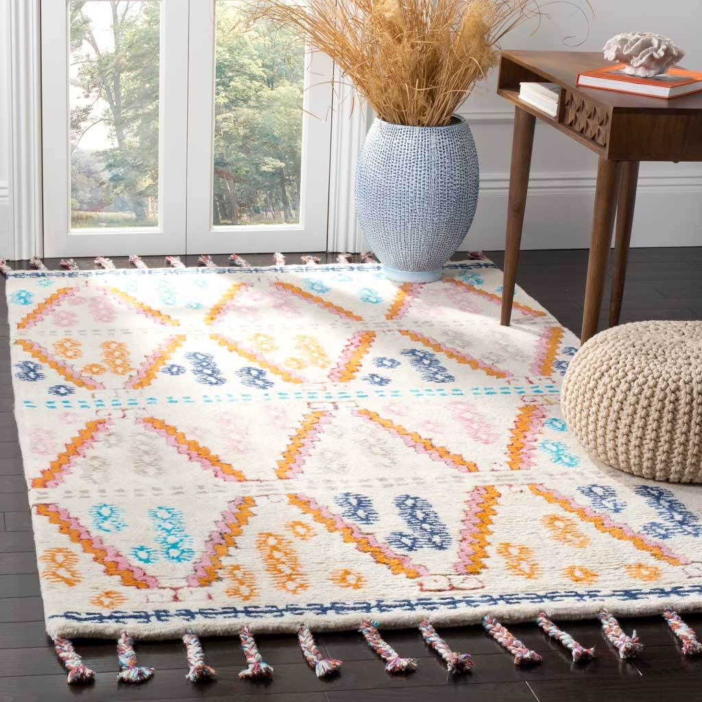 A hand-tufted ivory rug adds vibrant geometric texture and braided fringe beneath a wood side table.